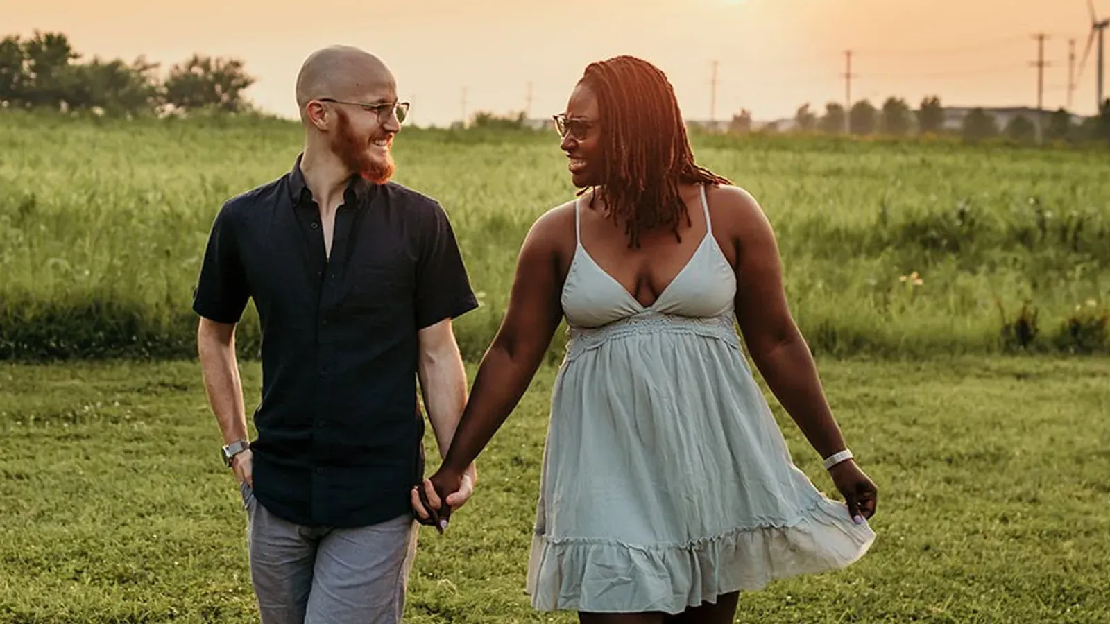 Kyana and Bailey Wilkinson, who own the agency, walking hand in hand through a field at sunset